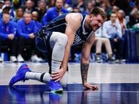 Dallas Mavericks guard Luka Doncic grabs his right foot after an awkward fall during the...