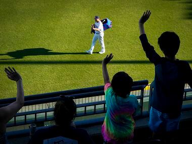 Fans wave to Round Rock Express catcher John Hicks as he takes the field to warm up at Dell...