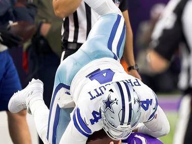 Dallas Cowboys quarterback Dak Prescott (4) is upended as he was driven out of bounds by...