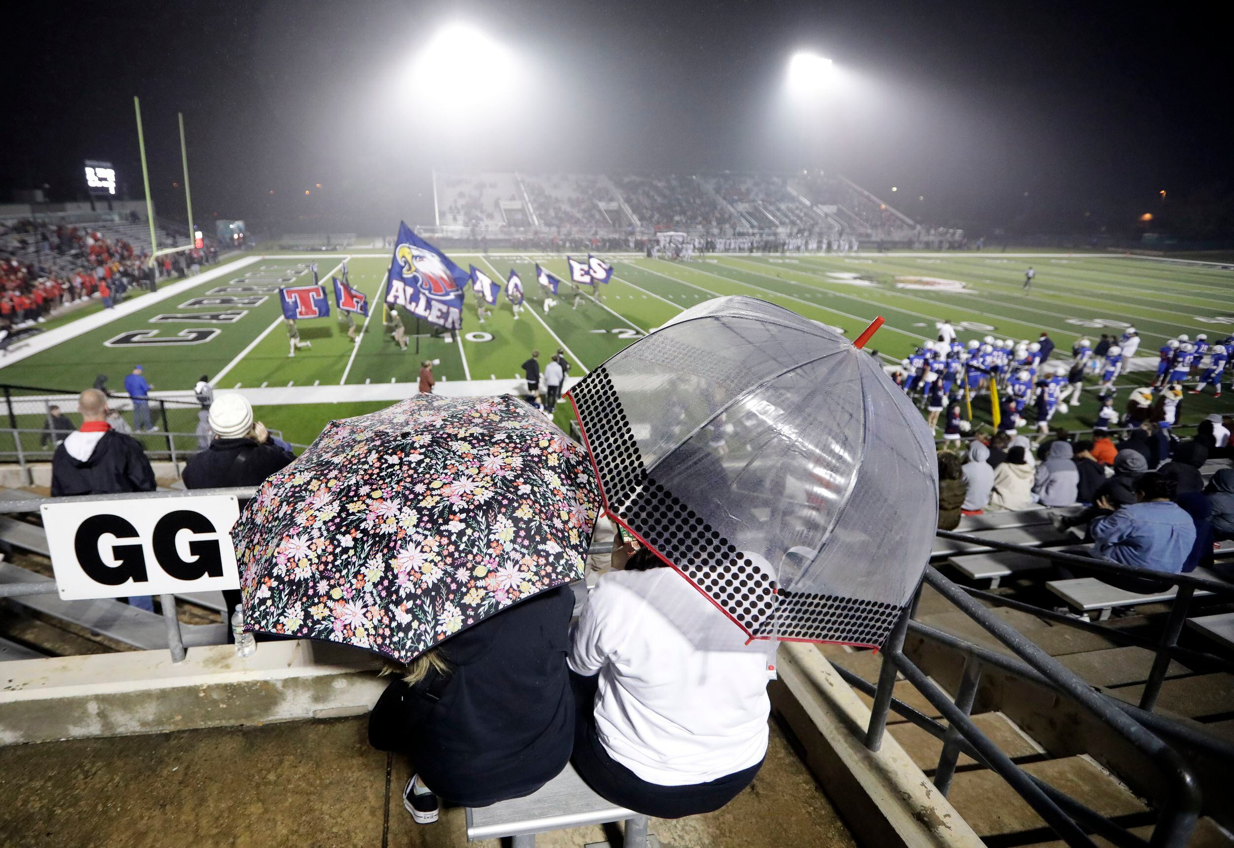 Arlington Martin fans Angie Green and Erica Hernandez take shelter from the heavy mist...