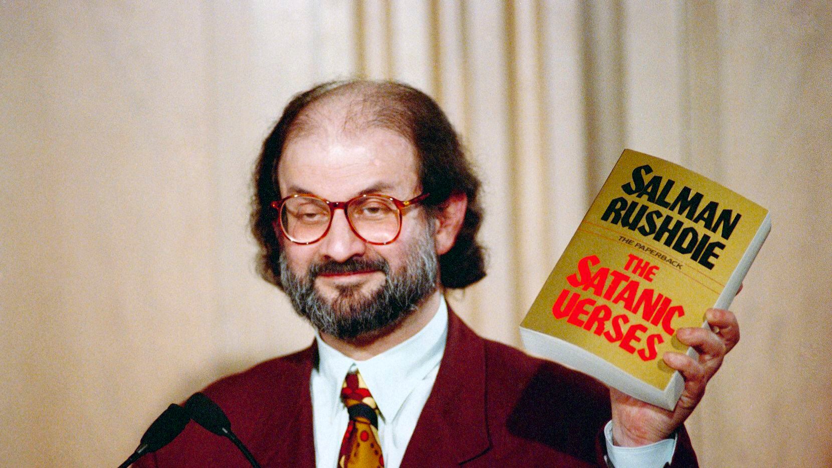 Salman Rushdie holds up a copy of his book "The Satanic Verses" at an event in Arlington,...
