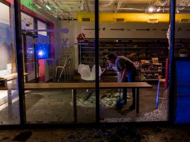 Anna Waugh  cleans up shattered glass from a business after tornado damage near the...
