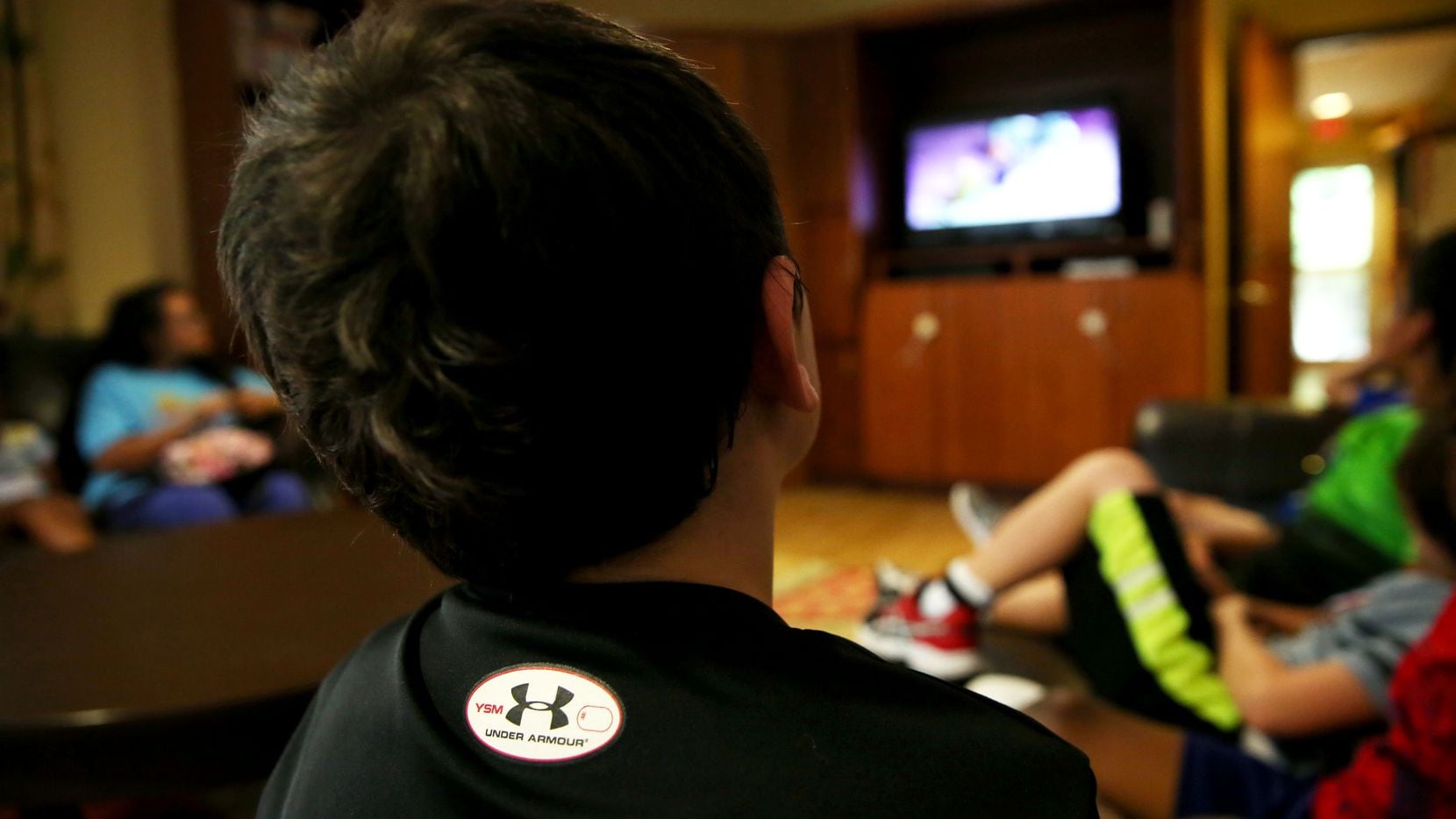 A boy watches TV at Jonathan's Place, which serves abused and neglected children, in Garland.