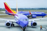 A Southwest Airlines plane is prepared to push back from the gate as another taxis toward a...