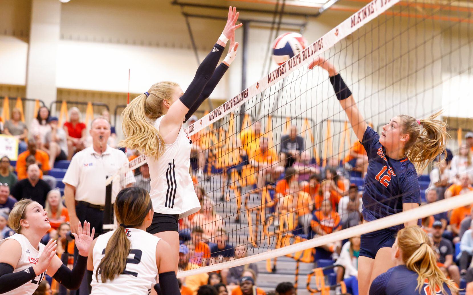 McKinney North Lily Nicholson (12) spikes the ball into defending Lovejoy players at a match...