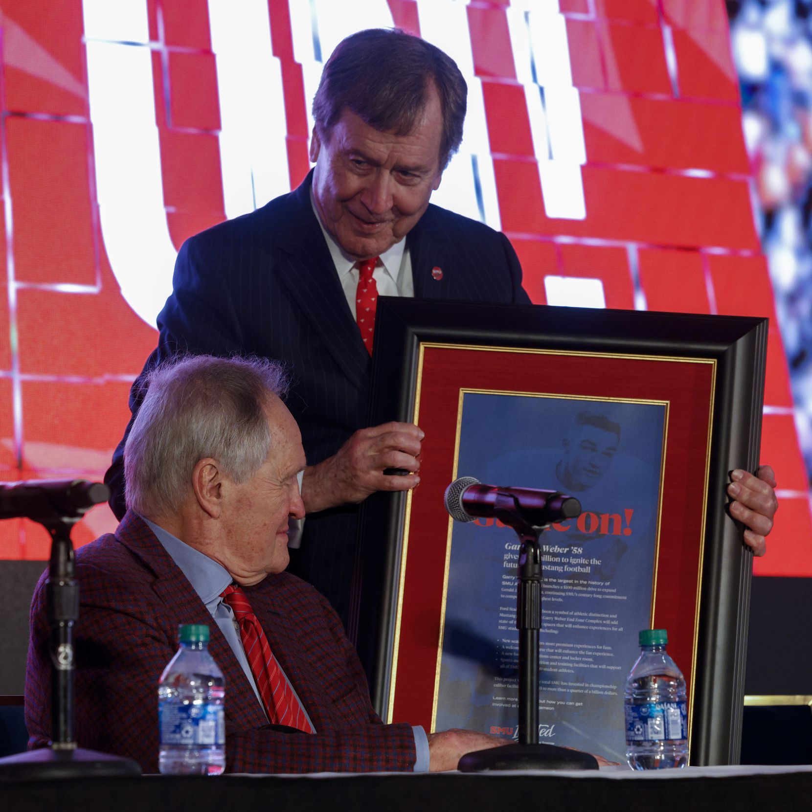 SMU President R. Gerald Turner presents SMU alumnus Garry Weber with a framed copy of a full...