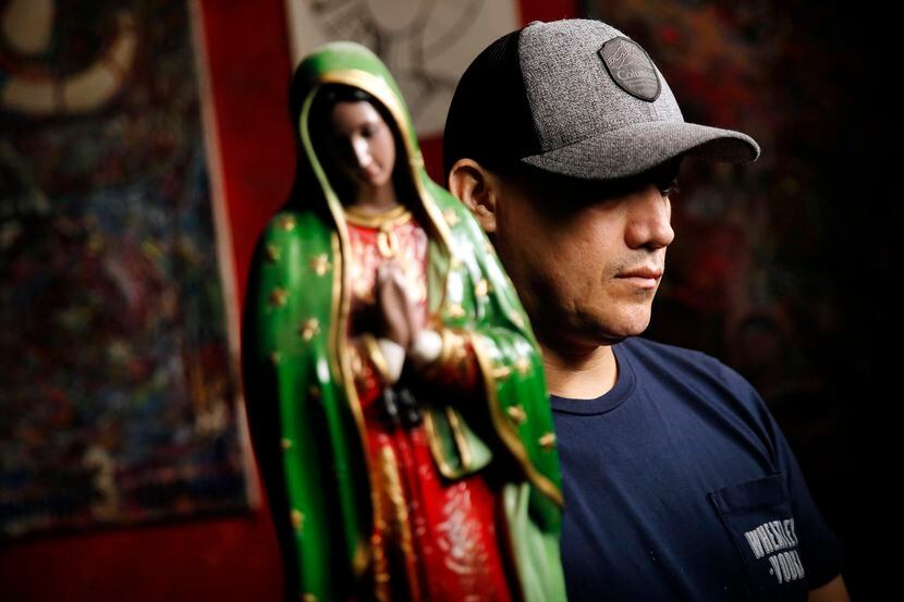 Juan, an undocumented worker, husband and father of four, is pictured with a statue of the...