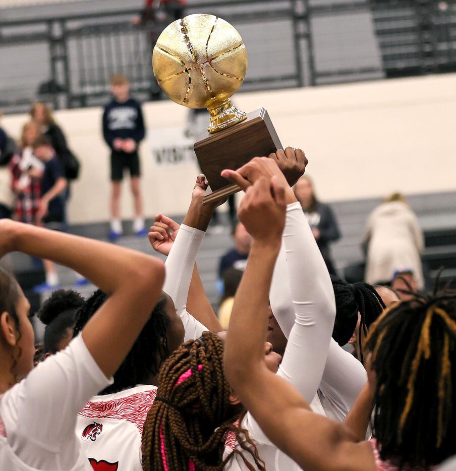 The Denton Braswell Lady Bengals hold up their trophy after defeating Flower Mound, 51-46 in...