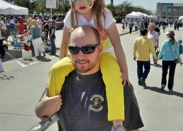 A girls rides on her father's shouldes at Arts in the Square in Frisco. 