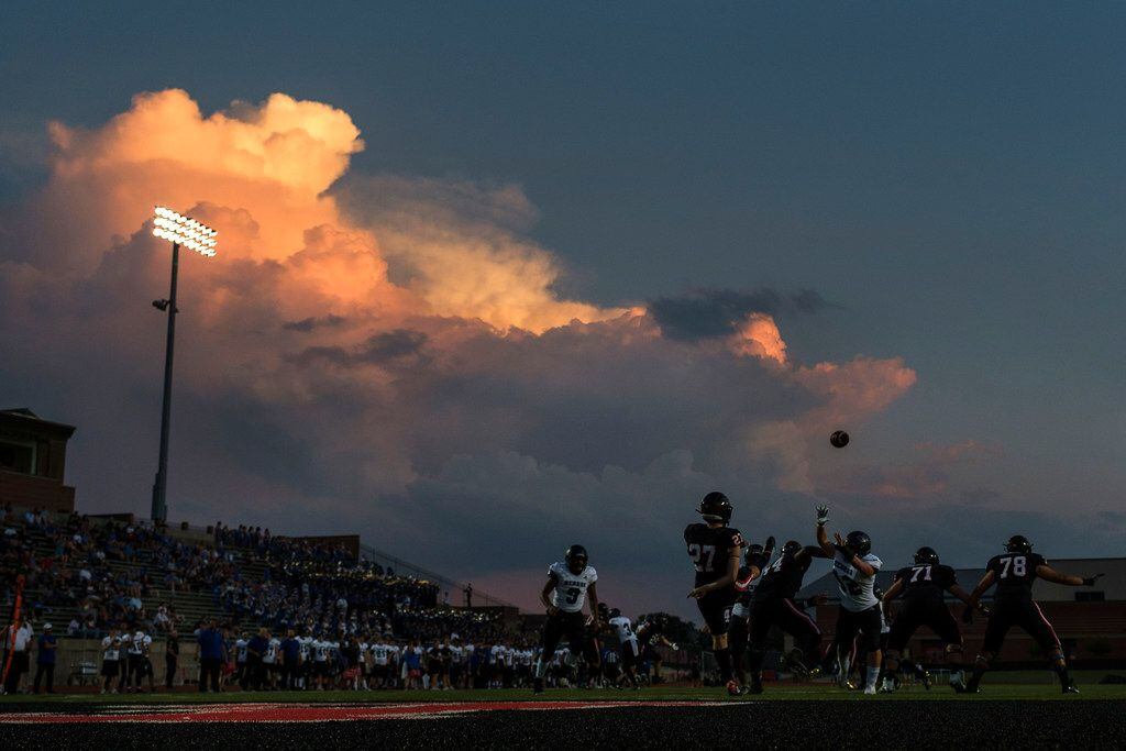Coppell punter Tyler Reid punts into the evening sky during the first half of a high school...