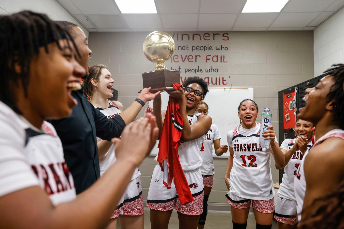 Braswell’s Alisa Williams, center, holding the trophy cheers alongside her teammates after...