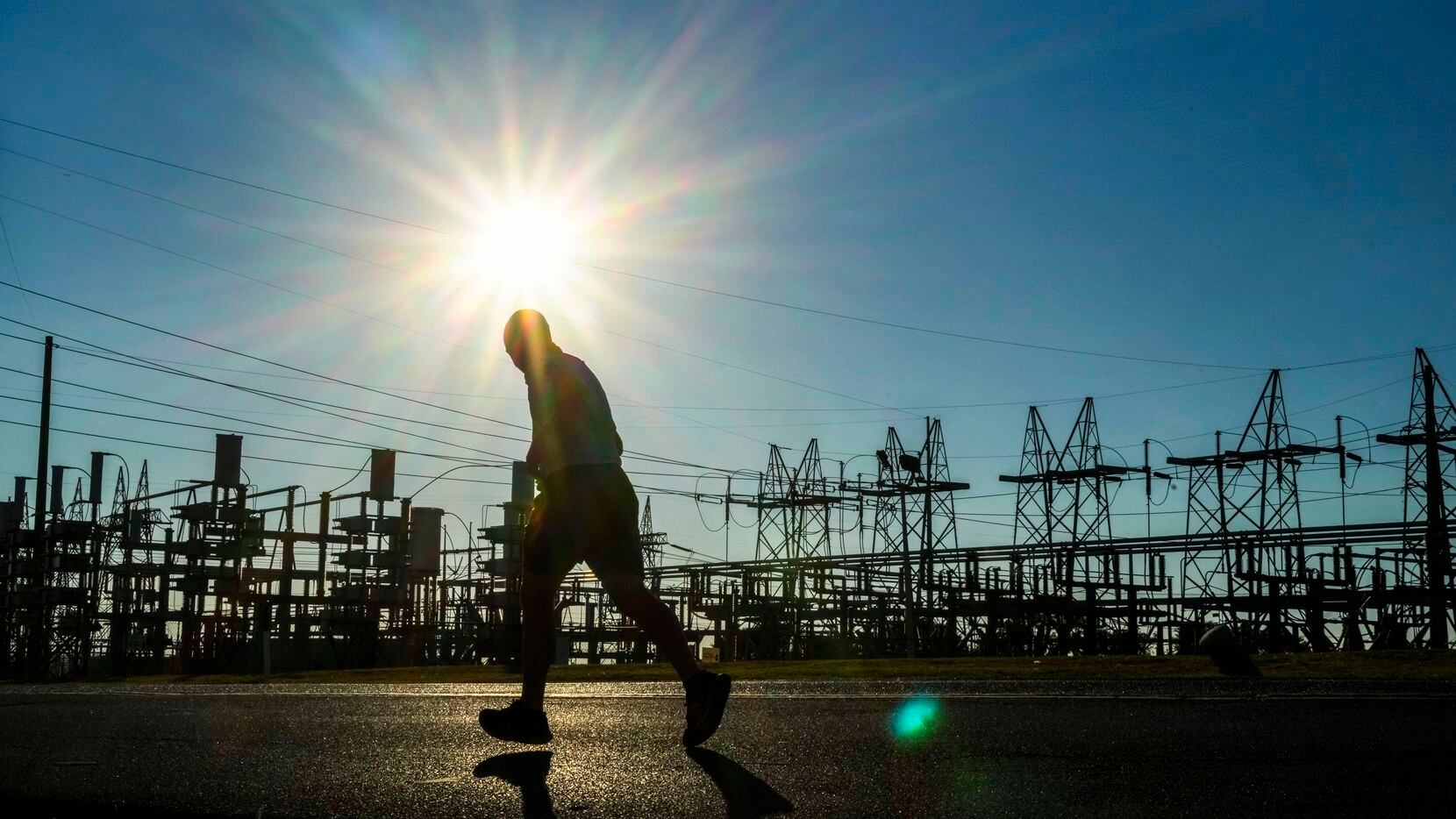 A runner passes the Oncor Cedar Hill Switchyard as the sun beats down on Monday, July 11,...
