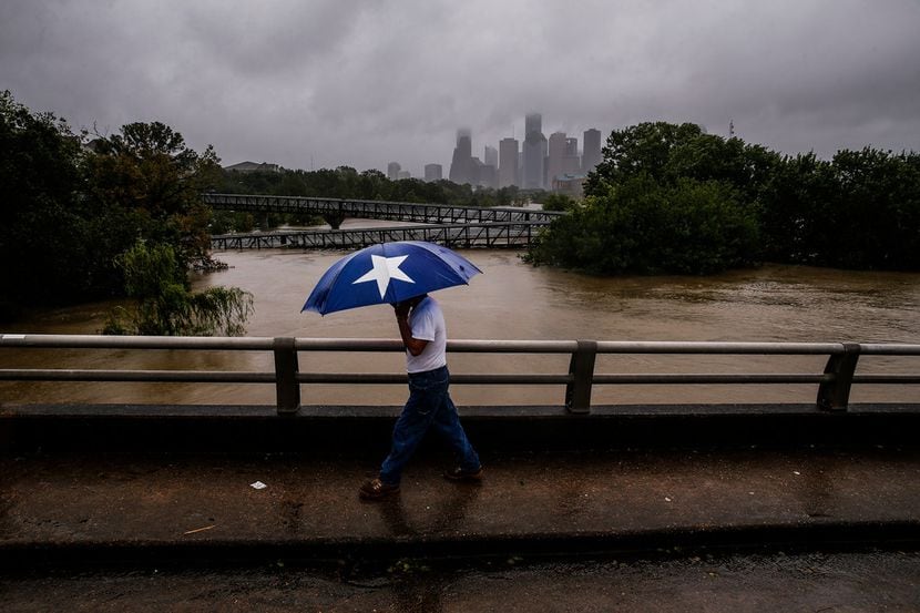 Armando Bustsamante walks along the street over Buffalo Bayou as floodwaters from Tropical...