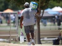A football enthusiast heads to one of the playing fields with iced drinks and water to help...