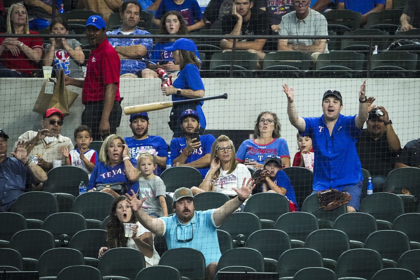 Fans are protected behind the netting as a bat flies out of the hands of Texas Rangers first...