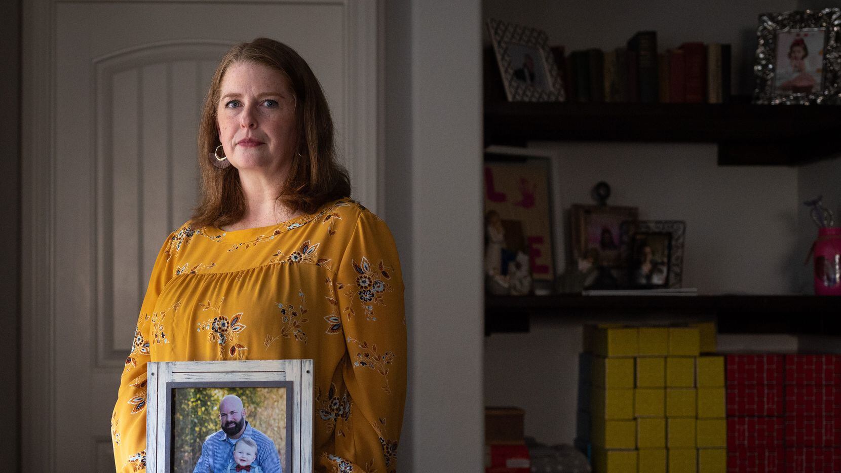 Katie McCoy poses Nov. 4, 2021, at her home in Forney with a photo of Dallas police Sgt. Bronc "Bronco" McCoy, the father of her children who died last year of causes related to COVID-19. Sgt. McCoy was the first Dallas police officer to die of the virus.