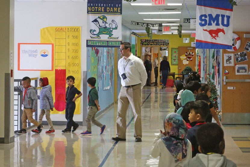 Teacher Assistant Adrian Rivera watches as students make their way through the hallways at...