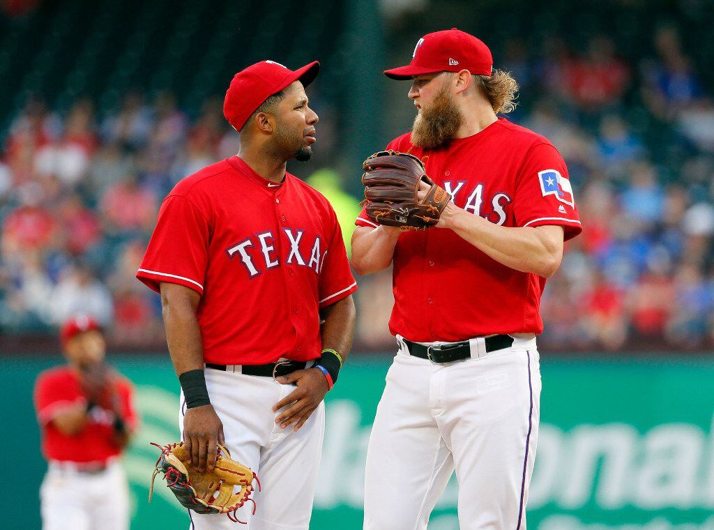 Texas Rangers' Elvis Andrus talks with starting pitcher Andrew Cashner, right, on the mound...