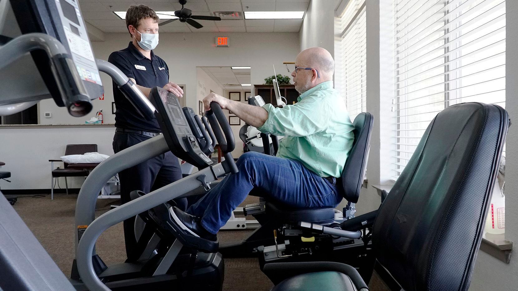 Dr. Brandon O’Malley demonstrates exercises with former patient Scott Amon at SporTherapy in...