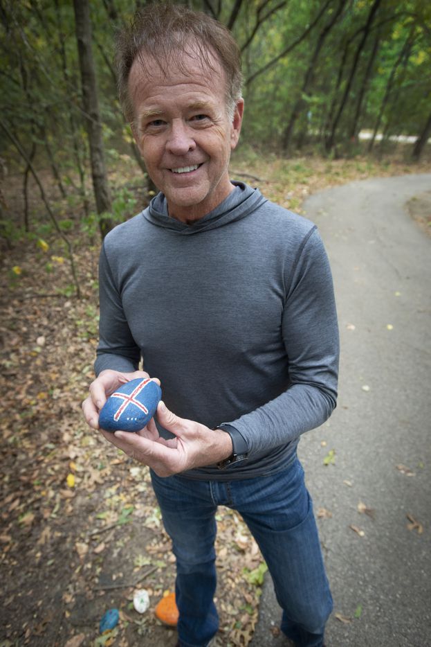 Ron Olsen, founder of the rock art trail, holds the first rock he painted with the flag of...