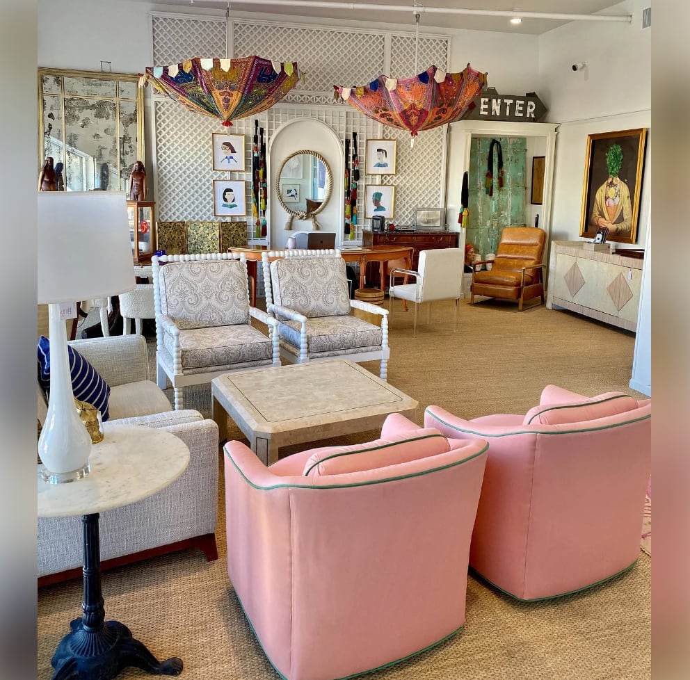 Pink chairs, a table, a lamp, and a set of chairs are in the showroom.