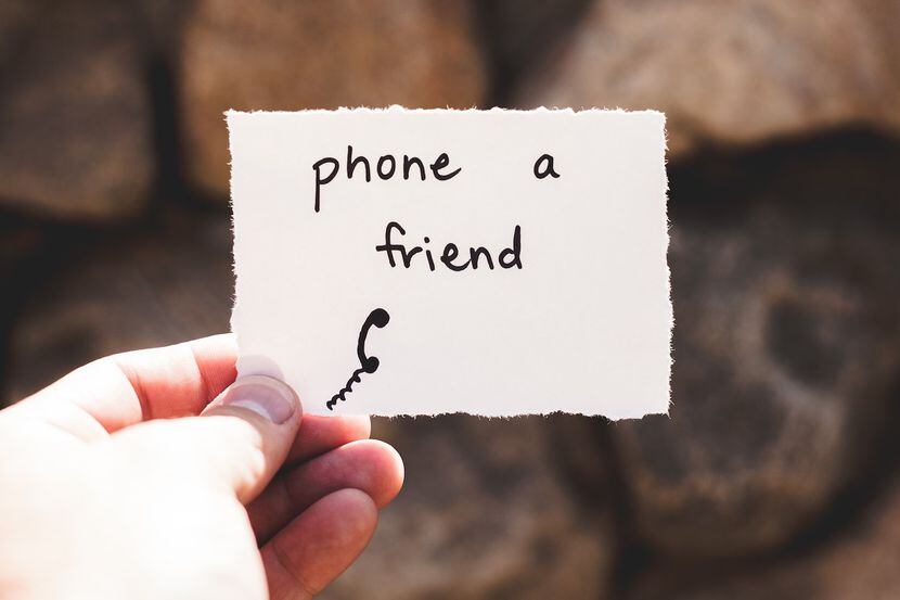hand holding a note that reads phone a friend