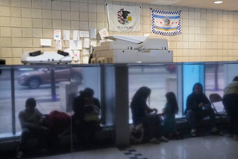 Immigrants from Venezuela are reflected in a marble wall while taking shelter at the Chicago...