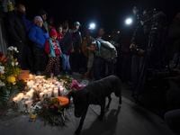 A migrant lights a candle during a vigil for the victims of a fire at an immigration...