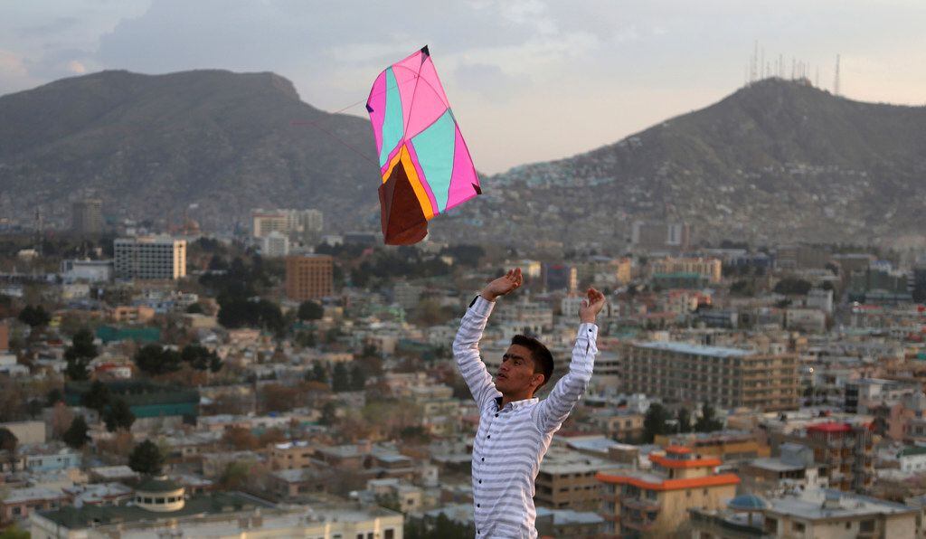 An Afghan launches a kite for his friend on hilltop during celebrations for Nowruz, the...