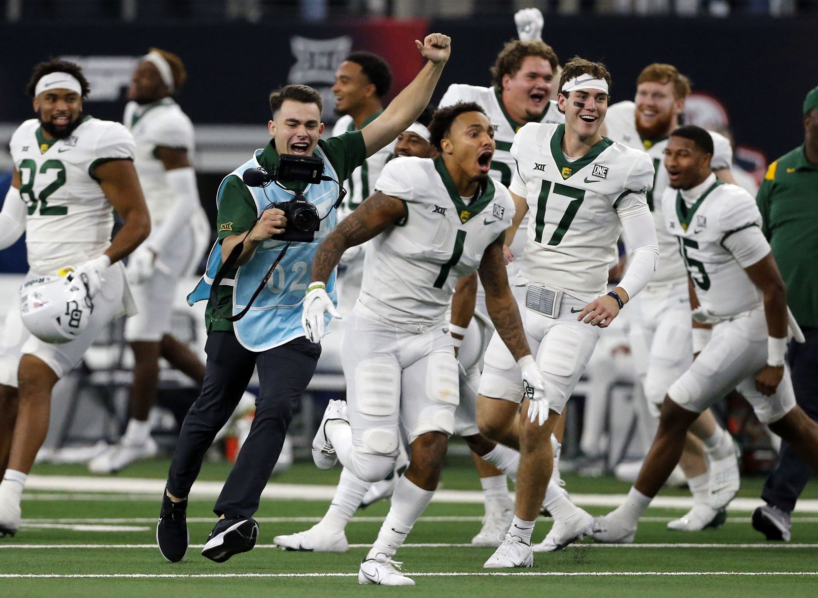 A school photographer (blue smock) celebrates with Baylor Bears running back Trestan Ebner (1) and the remainder of the Baylor bench at the end of  the Big 12 Championship football game against Oklahoma State at AT&T Stadium in Arlington on Saturday, December 4, 2021. Baylor won 21-16. (John F. Rhodes / Special Contributor)