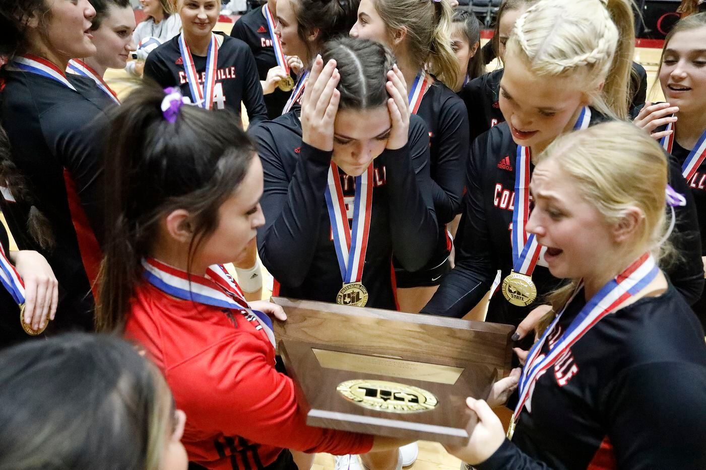 The Colleyville Heritage High School volleyball team looks over their state trophy after...