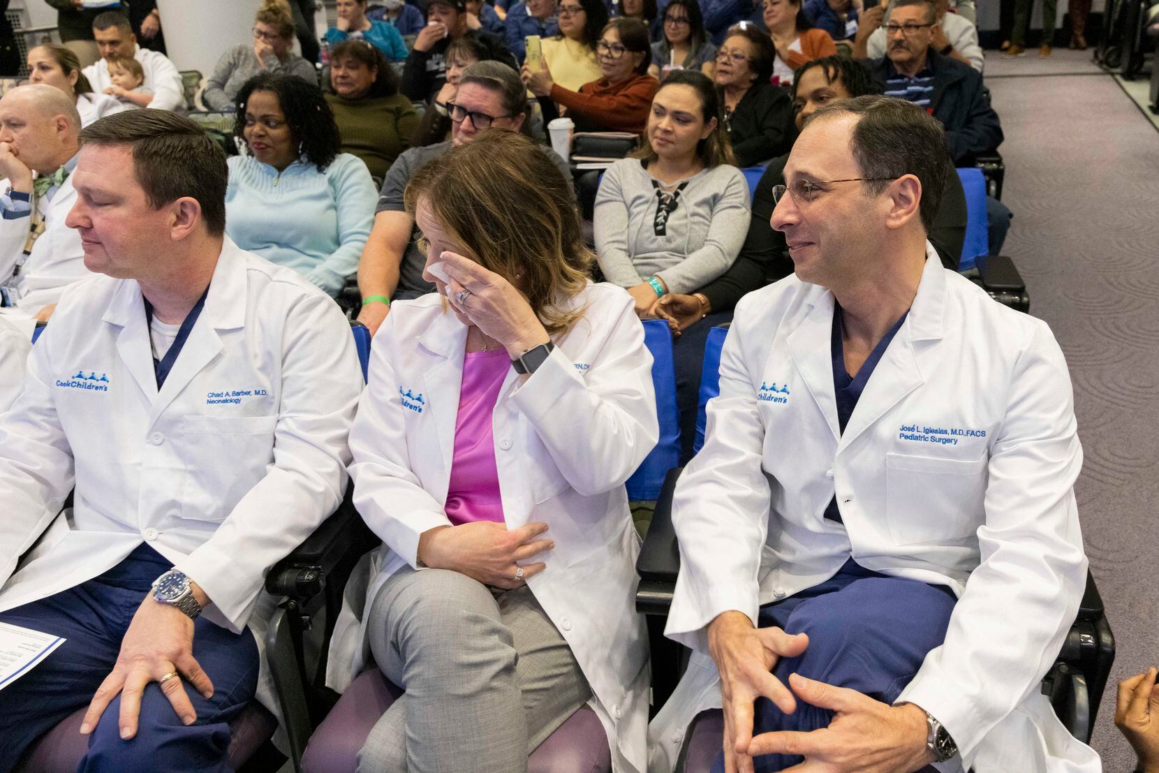 Valerie Gibbs (center), director of perioperative services, wipes away tears as a video...