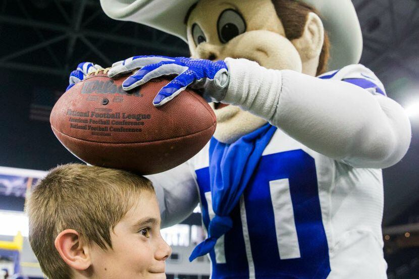 Dallas Cowboys mascot Rowdy signs a football on a boy's head  at The Star in Frisco. 