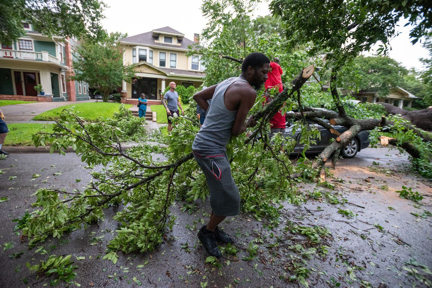 Ricky Neal, 40, drags branches while helping neighbors remove a tree piece by piece from his...