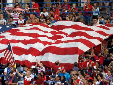 FC Dallas fans frame a Texas-sized American flag in the stands during the playing of the...