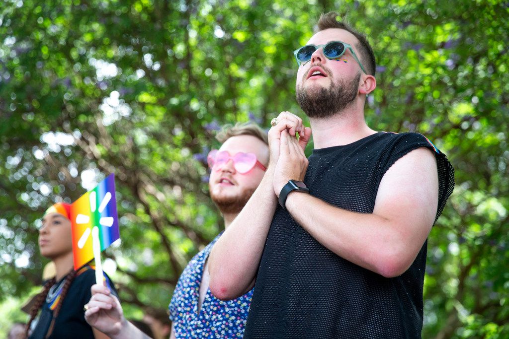 Alex Karshis, right, of Houston, watches the parade go by along with Sean Christopher, center, during the annual Dallas Pride / Alan Ross Texas Freedom Parade at Fair Park in Dallas on Sunday, June 2, 2019. (Shaban Athuman/Staff Photographer)