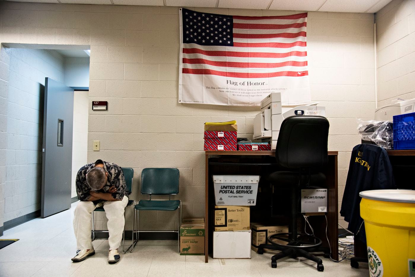 A man arrested by Immigration and Customs Enforcement agents waits to be processed at their...