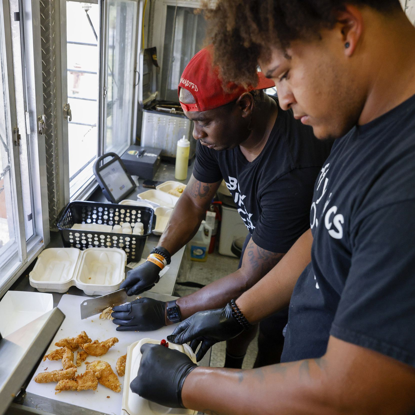 Vincent Meeks chops chicken as Nick Cantillo boxes an order of puffy tacos at Taco Wasted in...