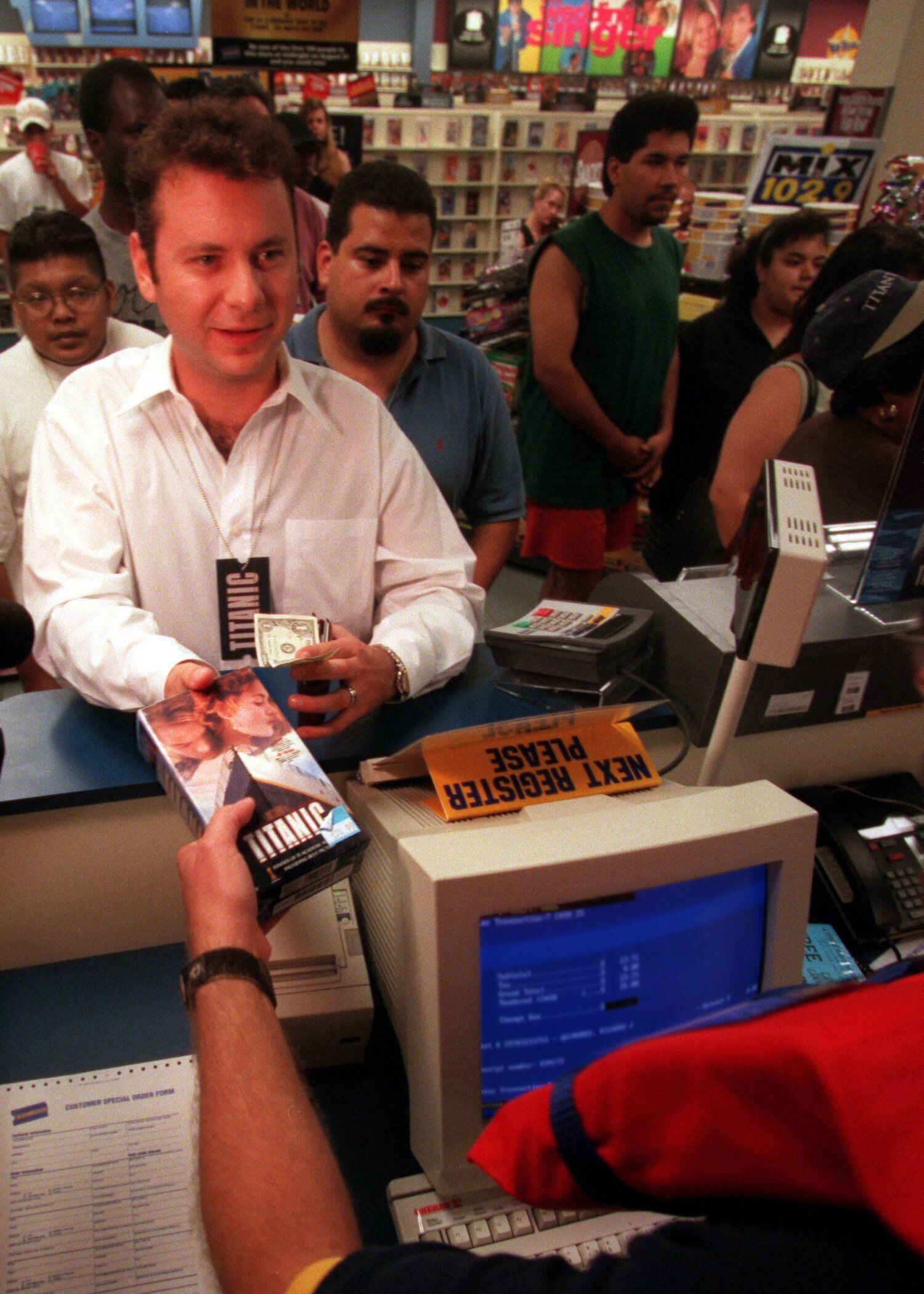 Rick Quinones (left) receives his copy of "Titanic" from Blockbuster employee Greg Hoeft at...