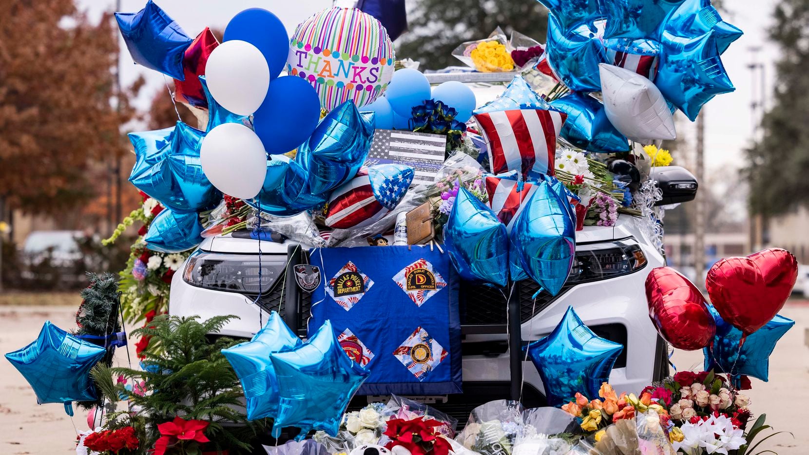 Tributes cover a patrol car as a memorial for Mesquite police Officer Richard Lee Houston II at the Mesquite Police Department on Saturday, Dec. 4, 2021, in Mesquite, Texas. Houston, a 21-year-veteran of the department, was shot and killed outside a grocery store a day earlier after responding to a disturbance call. (Juan Figueroa/The Dallas Morning News)