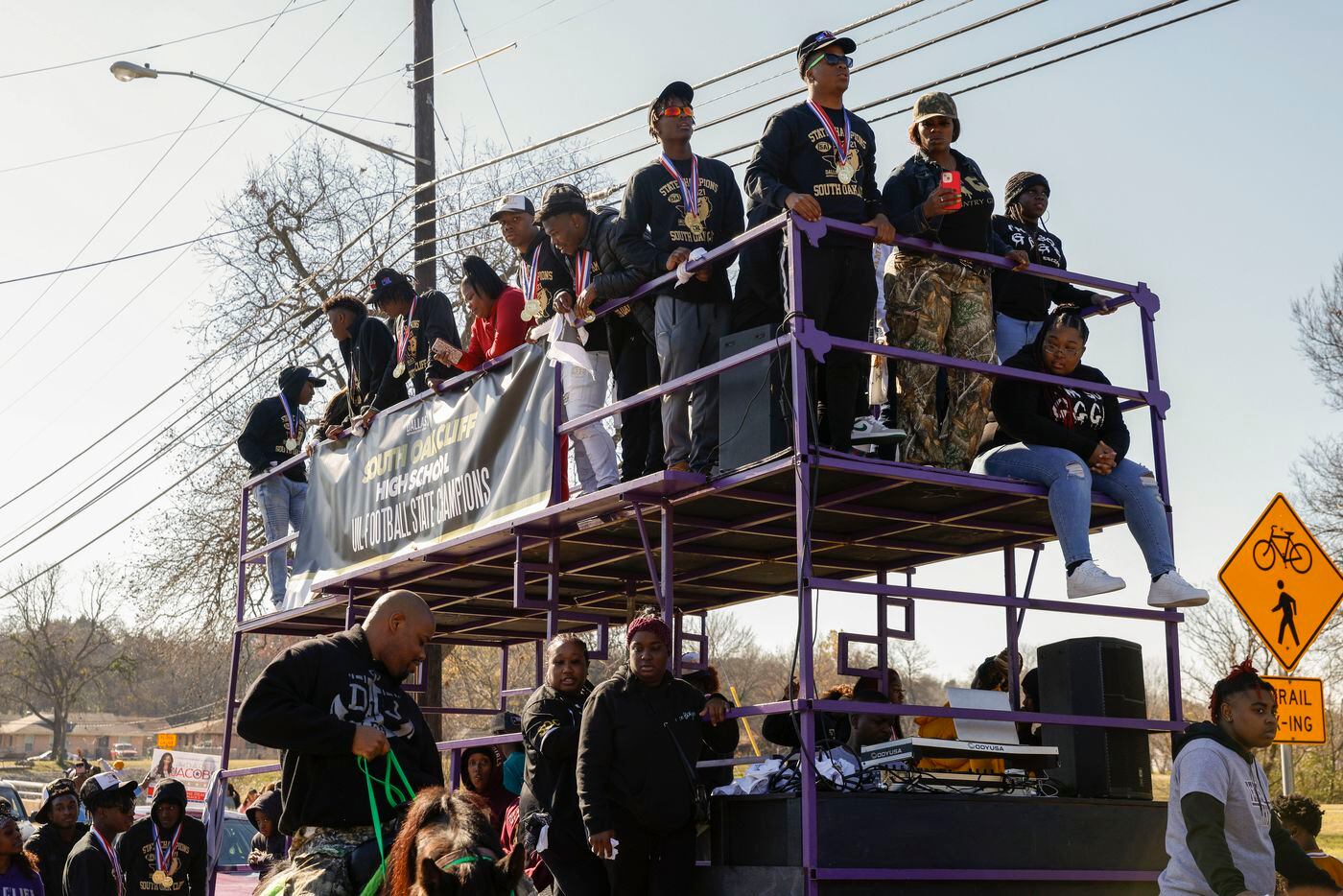 Members of the South Oak Cliff team stand on a two story trailer during a parade celebrating...