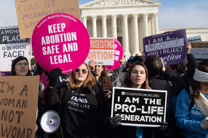 Abortion rights supporters hold signs alongside abortion opponents participating in the...
