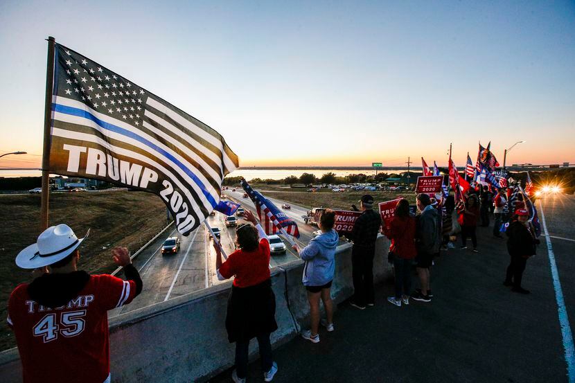 Members of the Trump Train 2020 DFW group wave flags and signs in support of Pres. Donald...