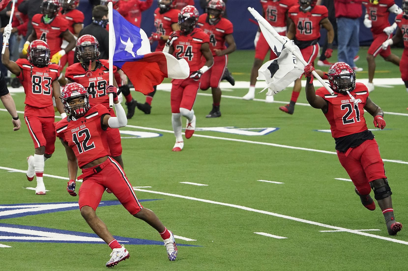 Cedar Hill’s Brian Rainey (12) and Kris Allen (21) carry flags as they lead their team on to the field to face Katy in Class 6A Division II state football championship  game at AT&T Stadium on Saturday, Jan. 16, 2021, in Arlington, Texas.