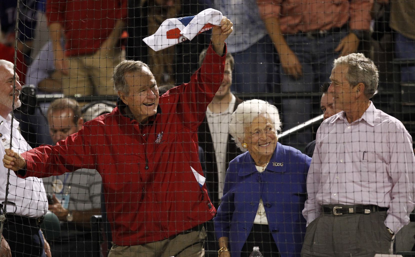 Former president George H.W. Bush waves a towel as wife Barbara and son George W. Bush look...