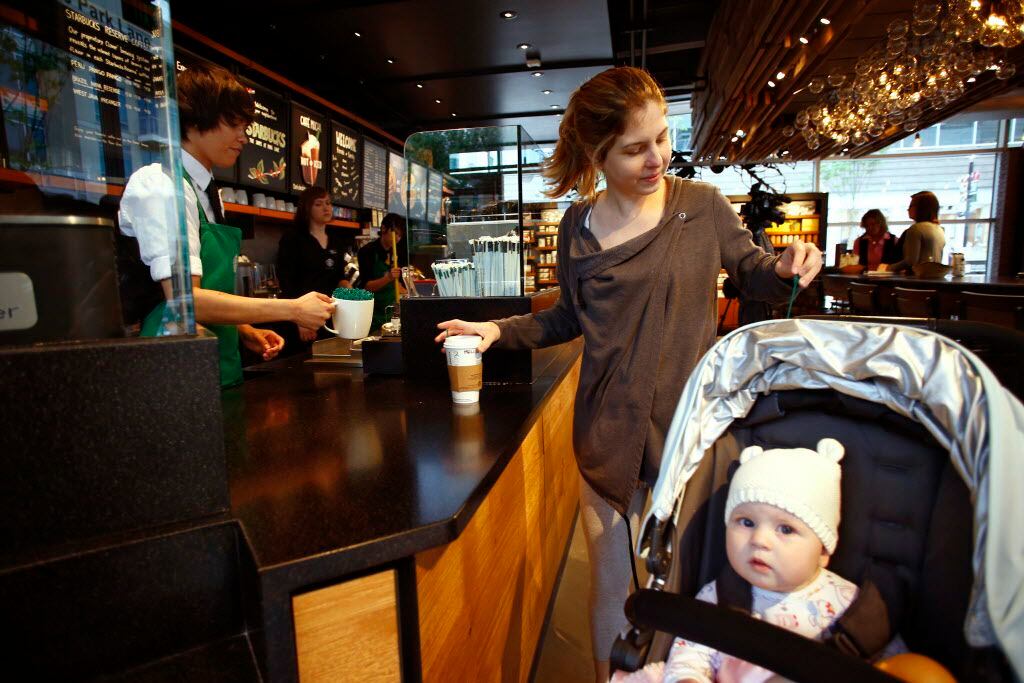 Melissa Cason (center) collects her coffee with her 8-month-old baby, Claire, on the opening...