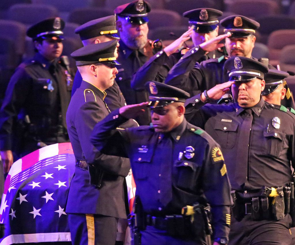 Dallas police officers salute their fallen comrade during the uniformed officers pass-by at...