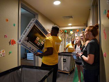 Student volunteer Joseph Lashley carries a flat screen TV for incoming freshman Makinley...