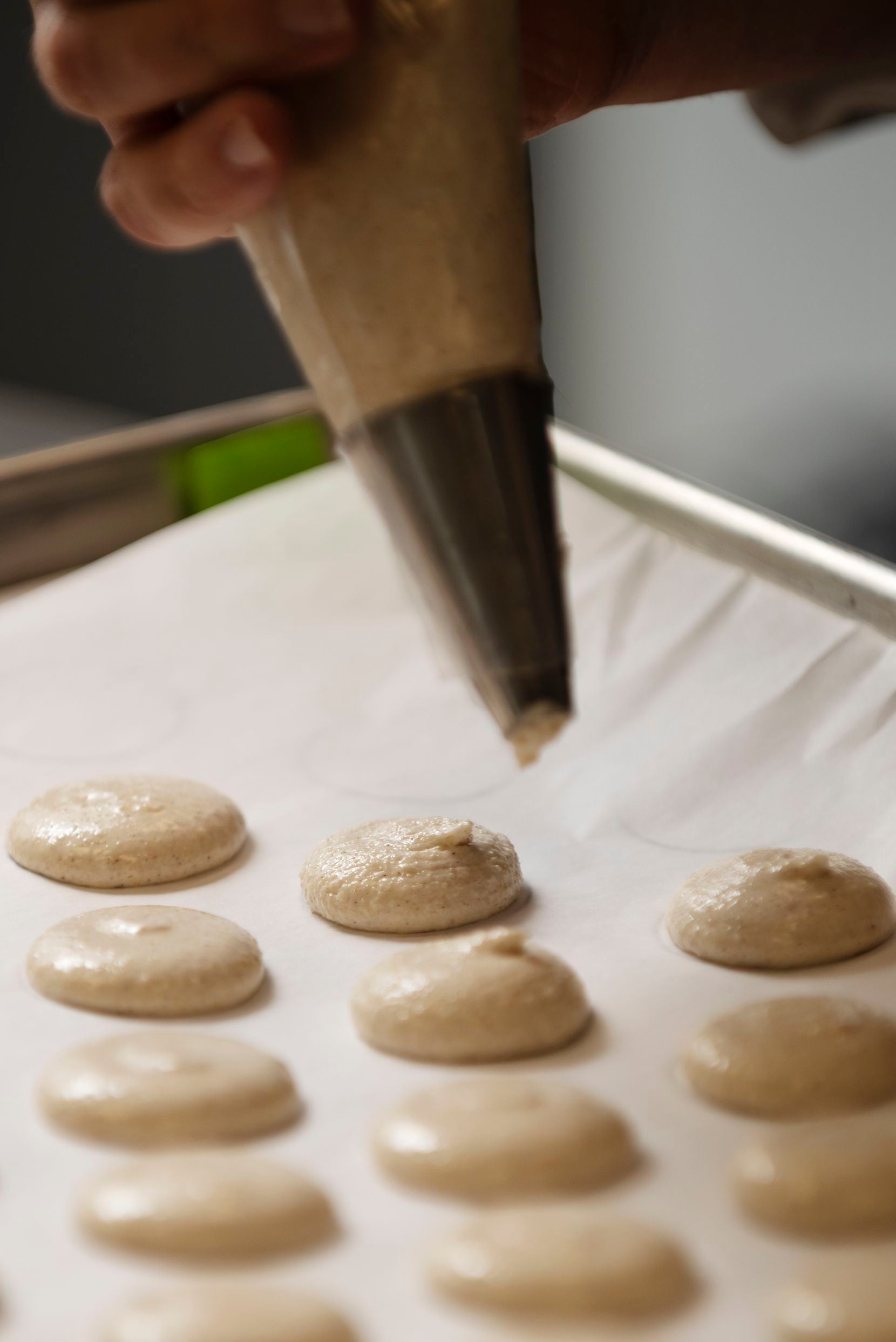 Andrea Meyer, of Bisous Bisous Patisserie, pipes macaron batter into small rounds on a baking sheet. 
