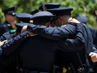 Dallas police officers huddle in prayer following funeral services for Dallas police Sr....